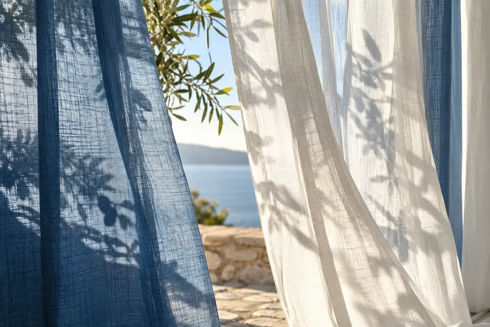 Blue and white curtains crossed by soft leaf shadows