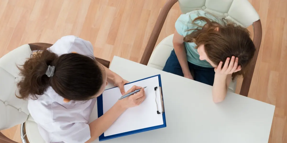 A healthcare professional listens and takes notes during a consultation.
