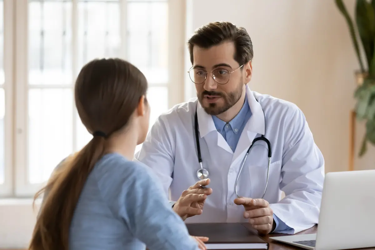 A doctor talks with a person during an appointment.
