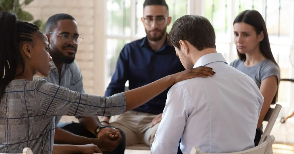 Adults sit together in a small supportive discussion group.