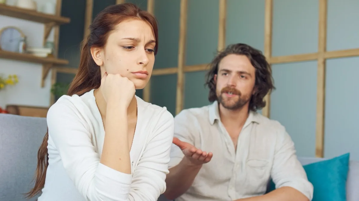 A couple talks through a disagreement while sitting on a sofa.