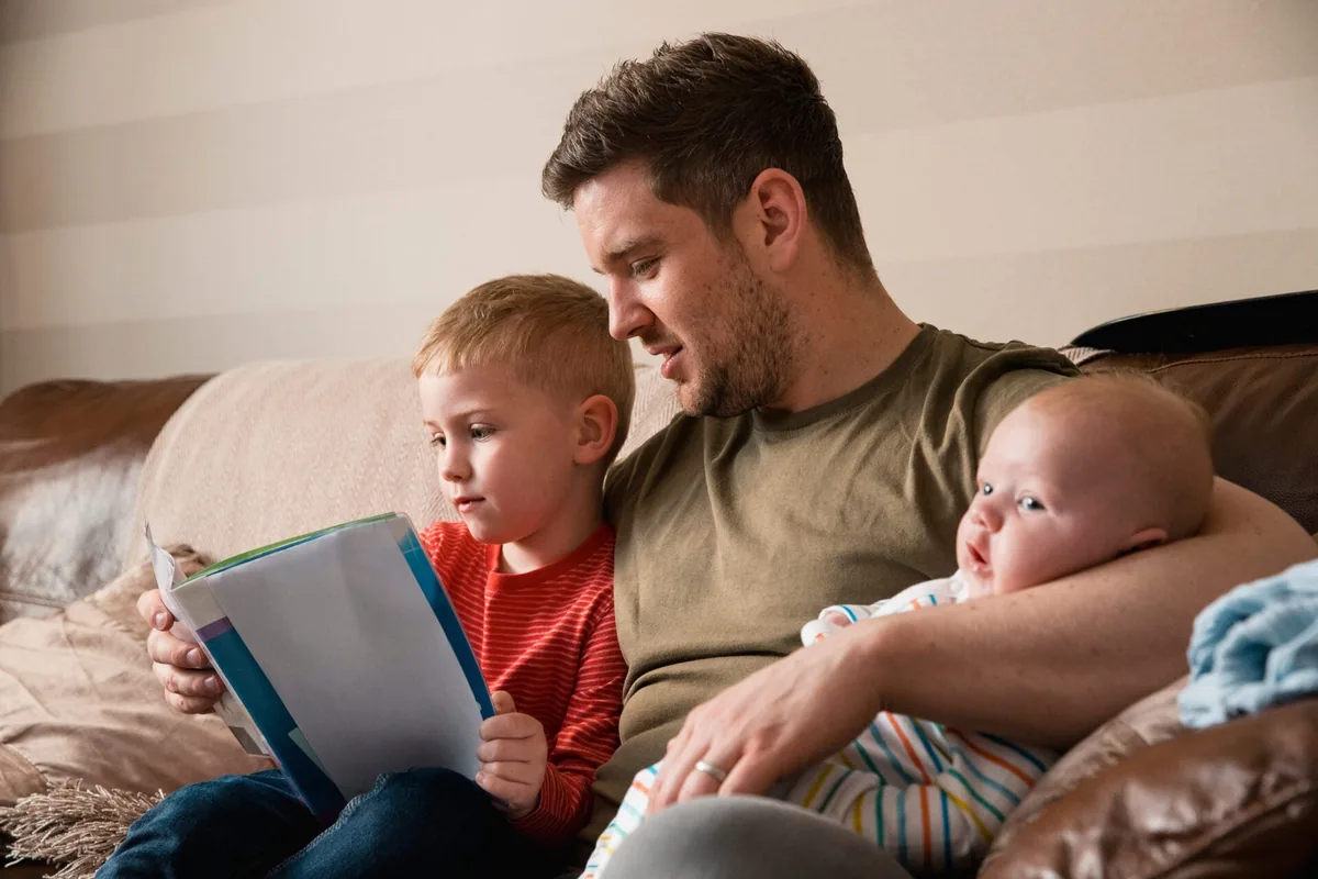 A father reads a book with his two children.