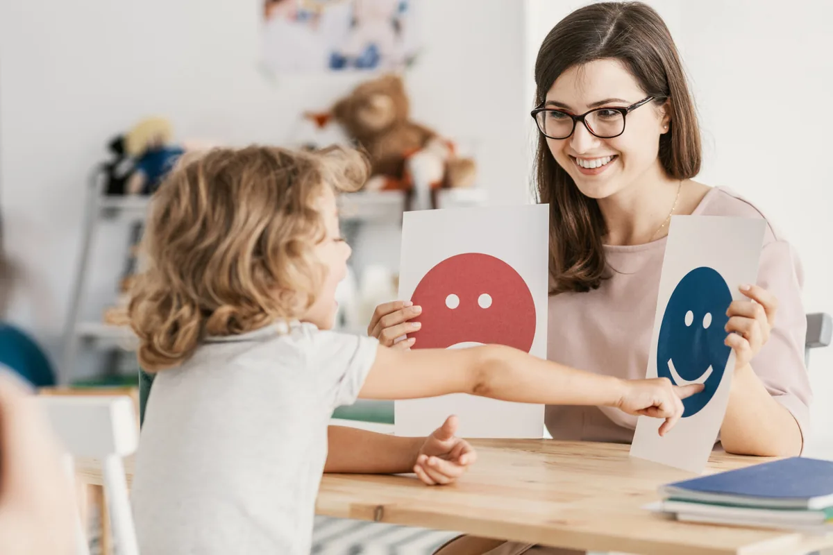 An adult helps a child explore emotions using colorful cards.
