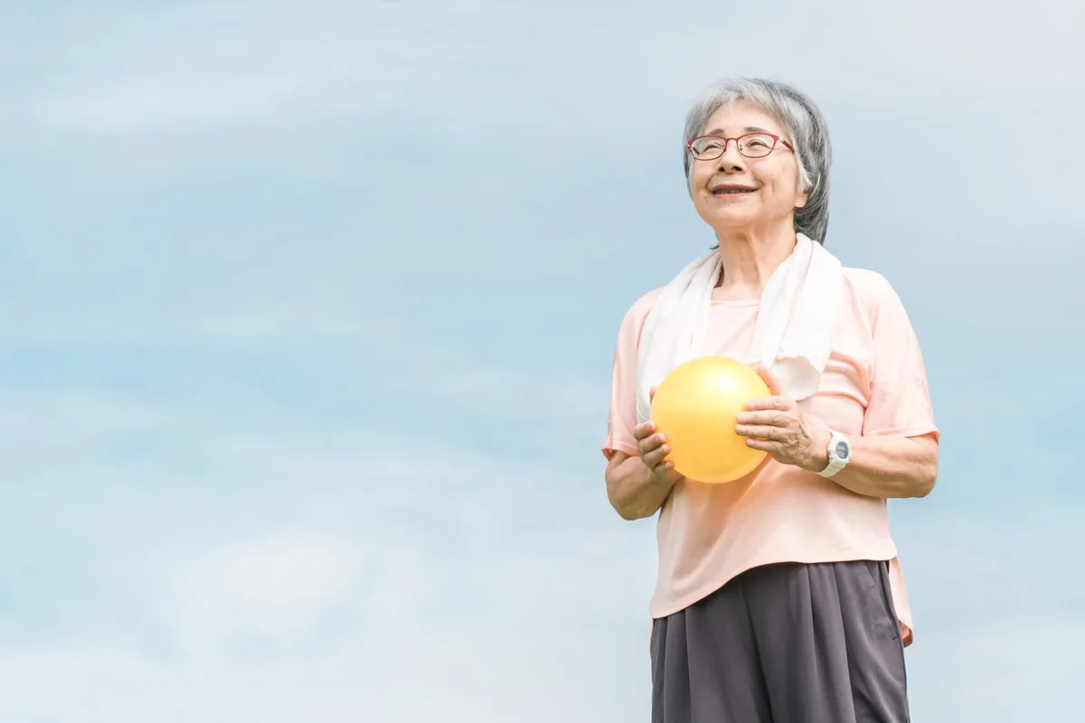An older woman holds a water bottle during a walk outdoors.