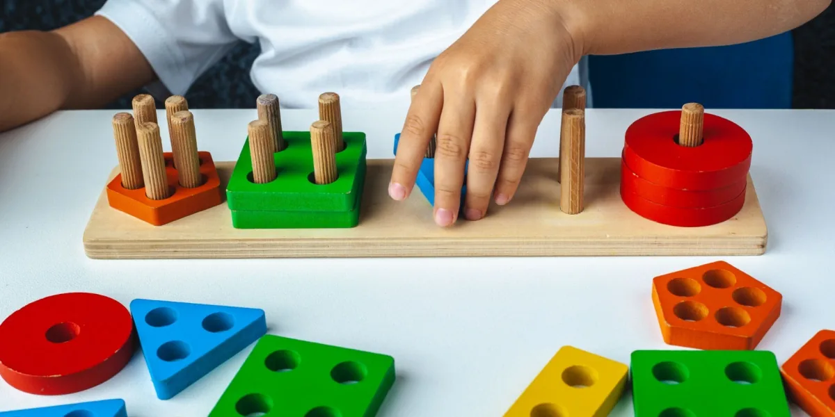 A child works with colorful shapes and wooden learning materials.