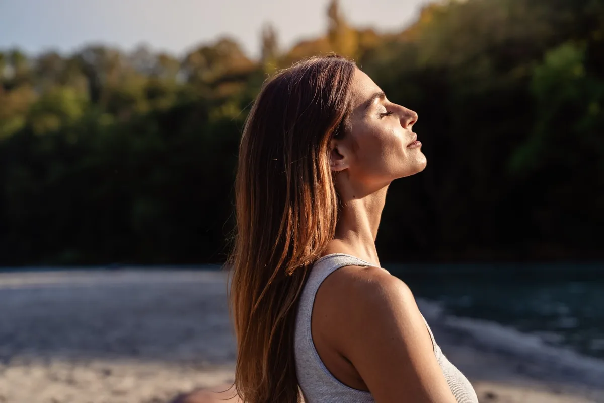 A woman closes her eyes and breathes in the evening light.