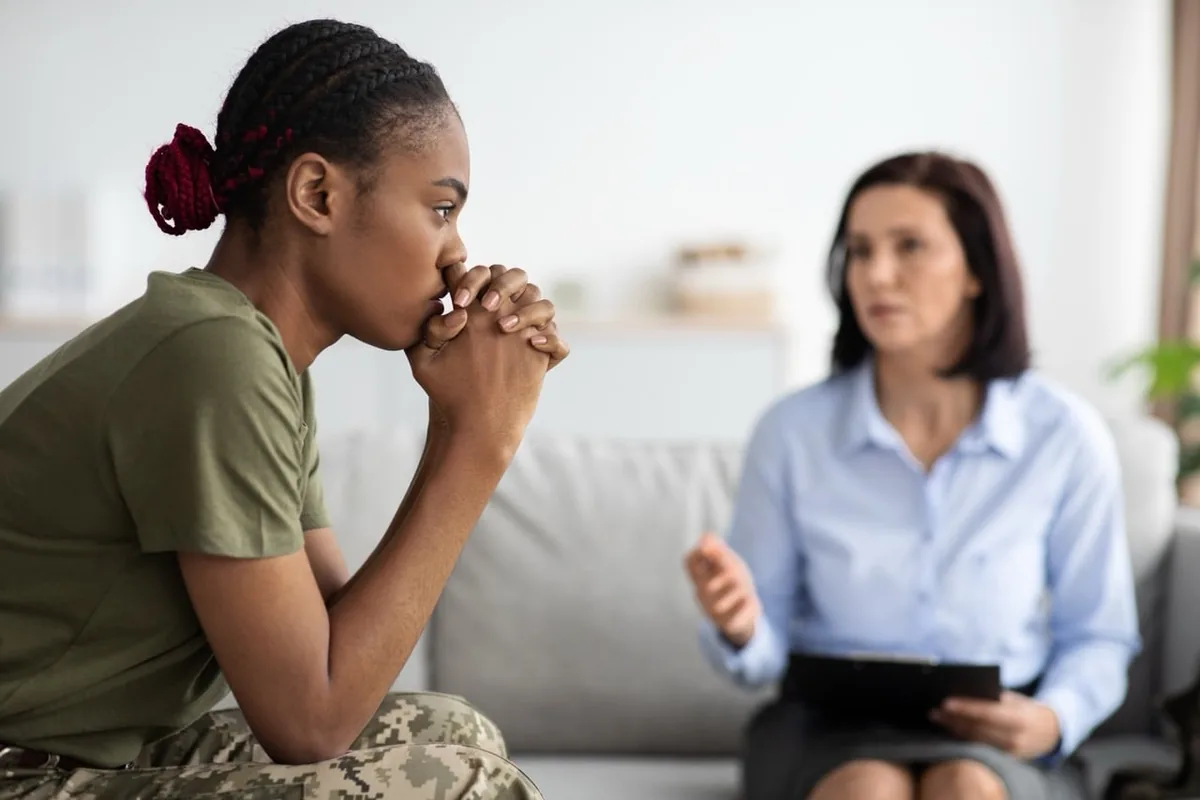A woman speaks with a counselor in a bright consultation room.
