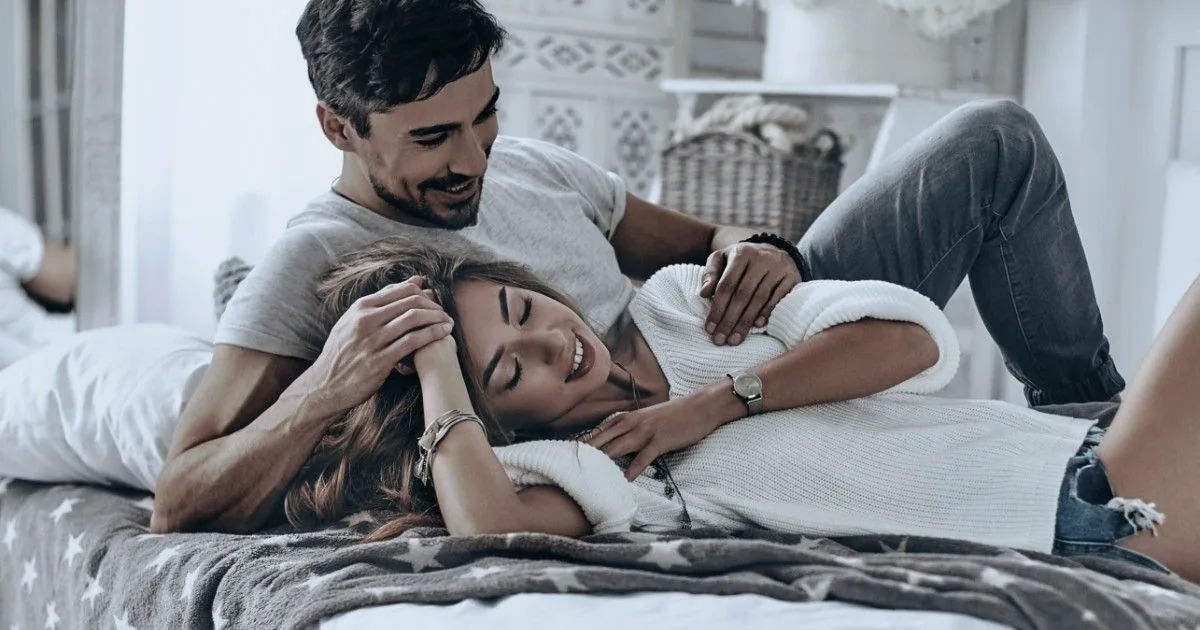 A couple relaxes together on a sofa.