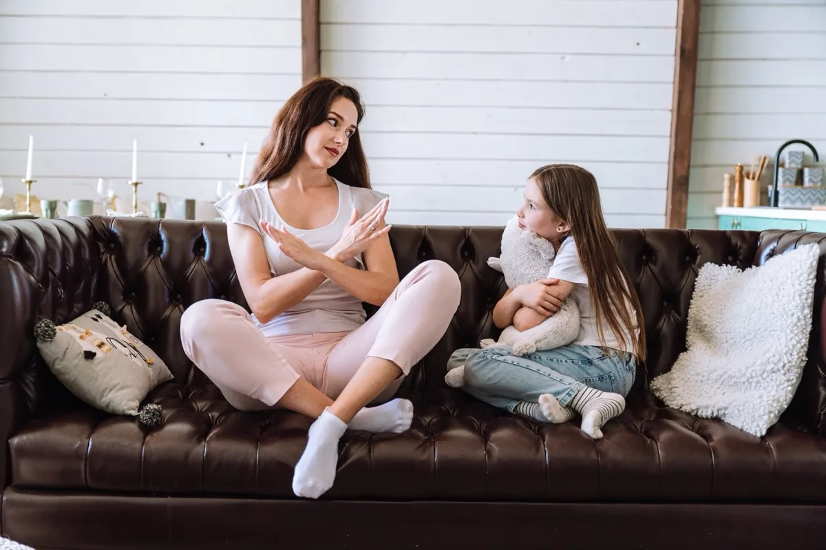 Two women sit together and discuss something at home.