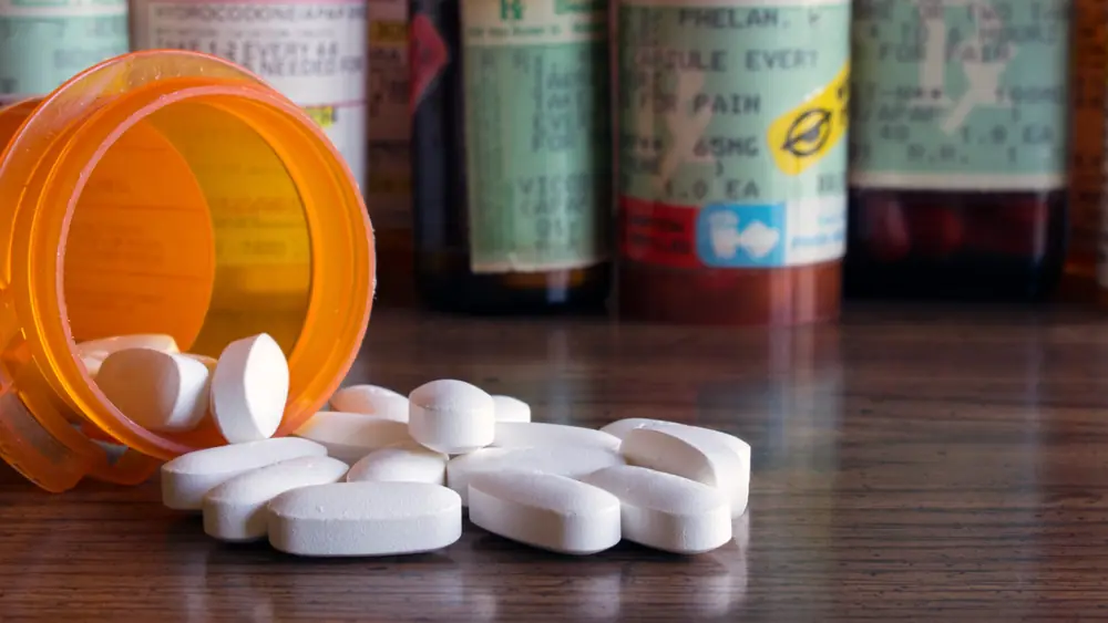 White tablets lie beside an orange medicine bottle.