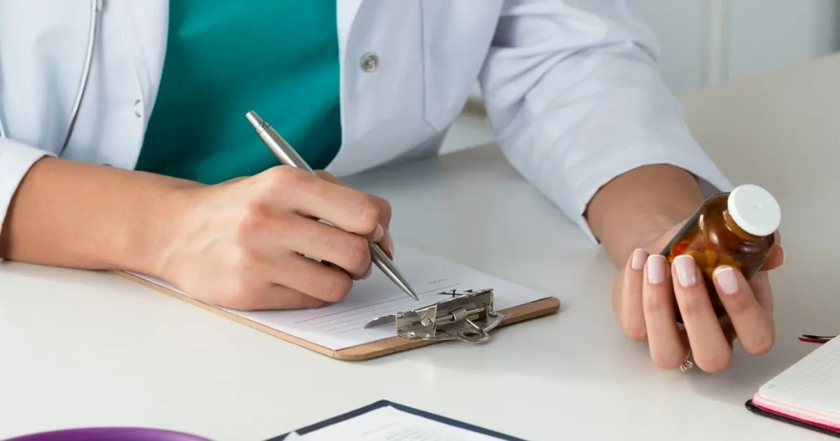 A healthcare professional writes notes beside a medicine bottle.