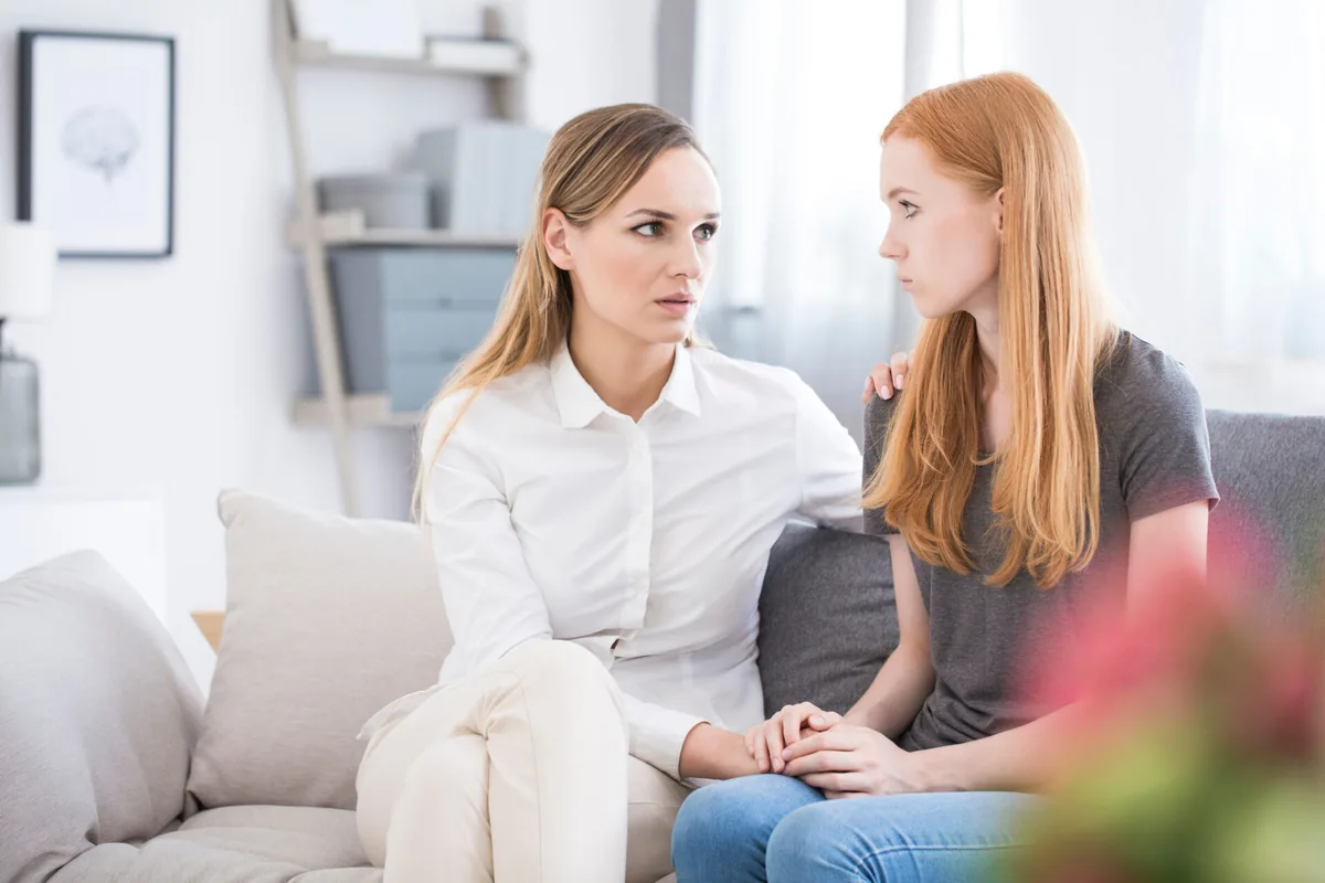 A healthcare professional listens to a woman in a consultation room.