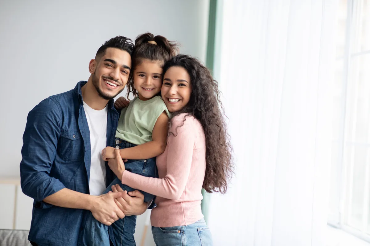 Parents and a child share a close hug at home.