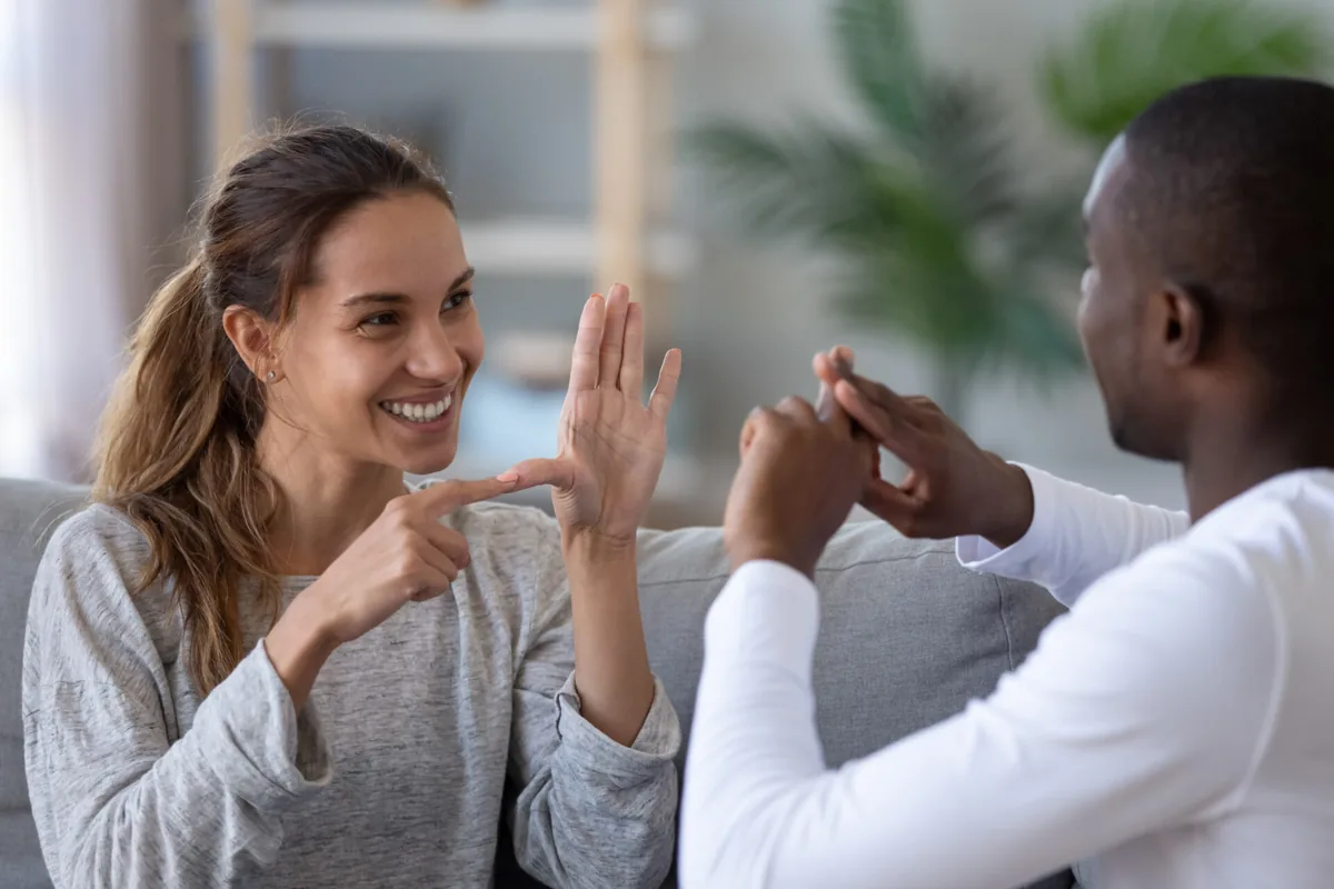 A young adult and an educator smile during a conversation.