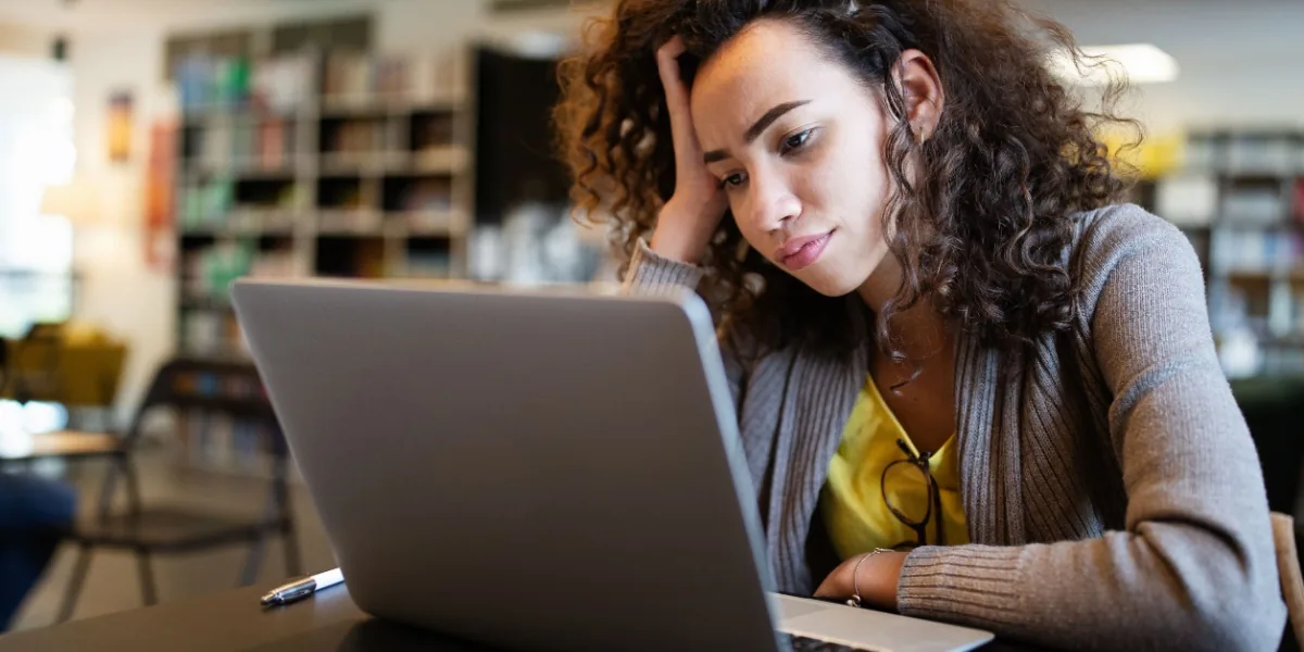 A woman uses a laptop at a cafe table.