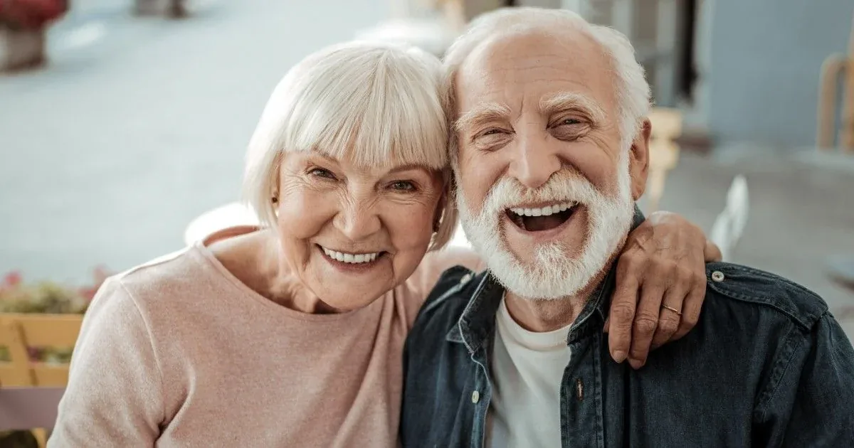 An older couple shares a laugh outdoors.