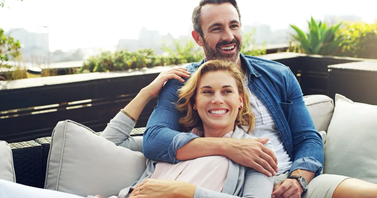 A couple relaxes together on an outdoor sofa.