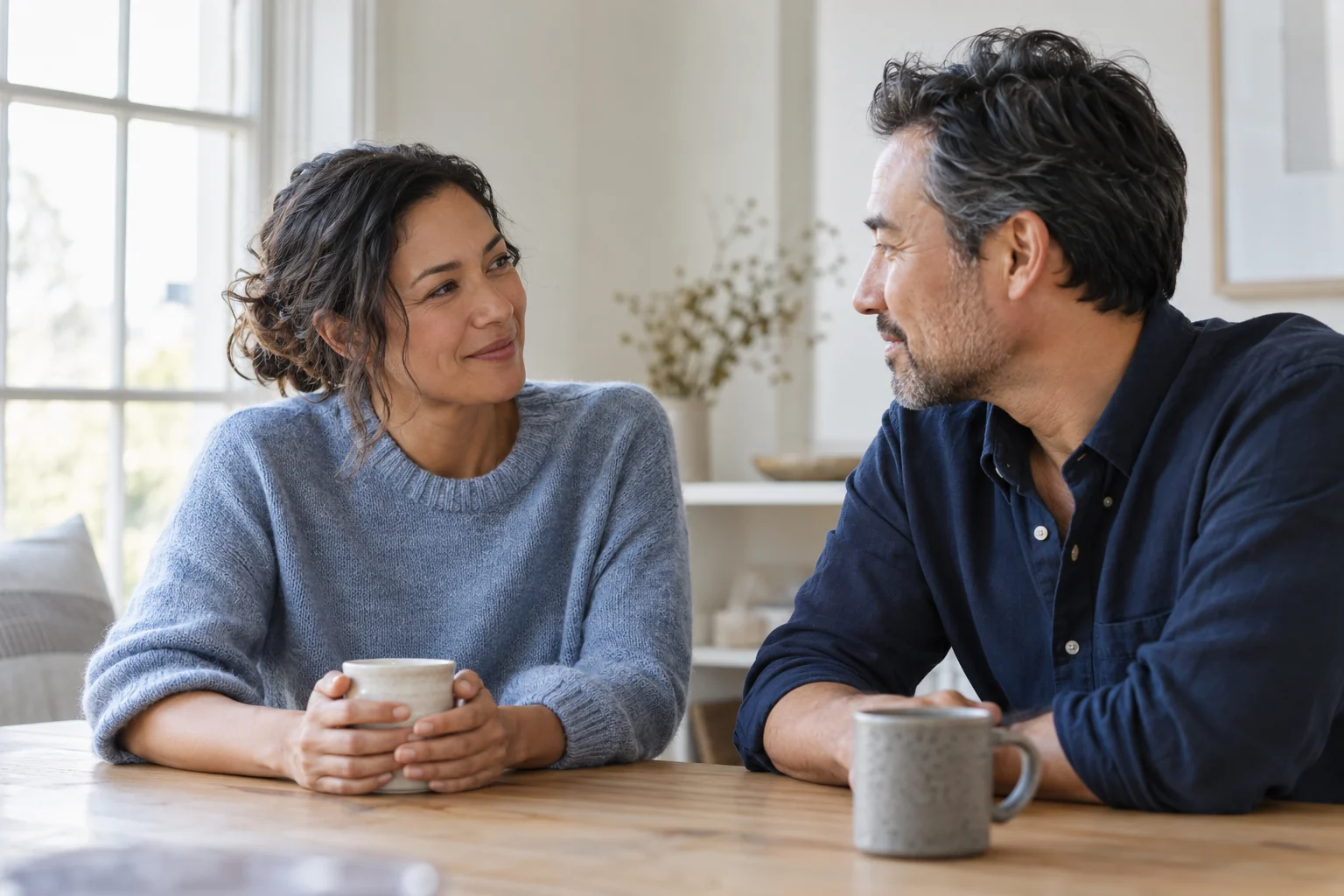 Two adults sharing a relaxed conversation by a sunlit window