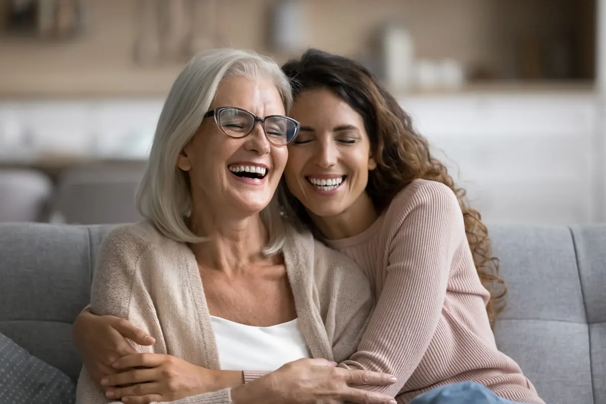 Two women of different generations share a warm embrace.
