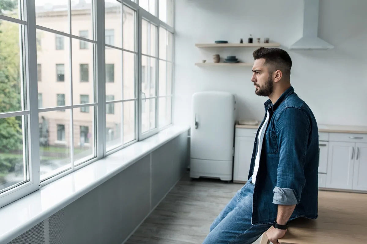 A man looks out from a bright office window.