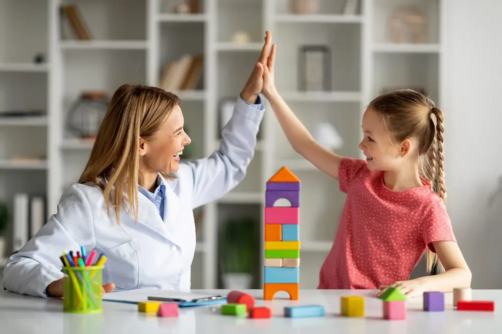 A child and an educator work together at a classroom table.