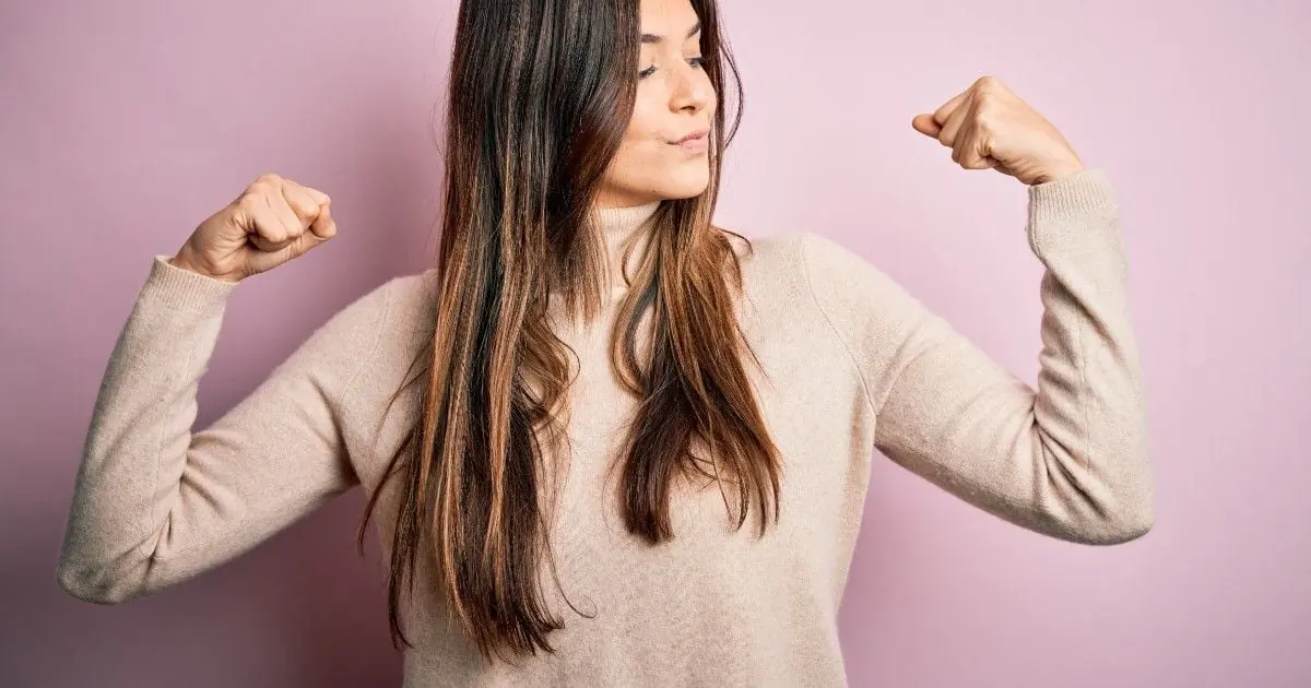A woman raises her arms in a playful gesture of strength.