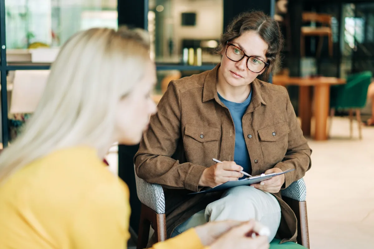 A counselor listens and takes notes during a conversation.