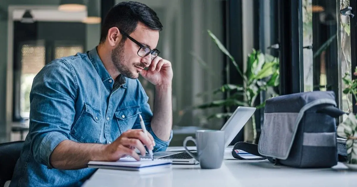 A man concentrates on a laptop at a desk.