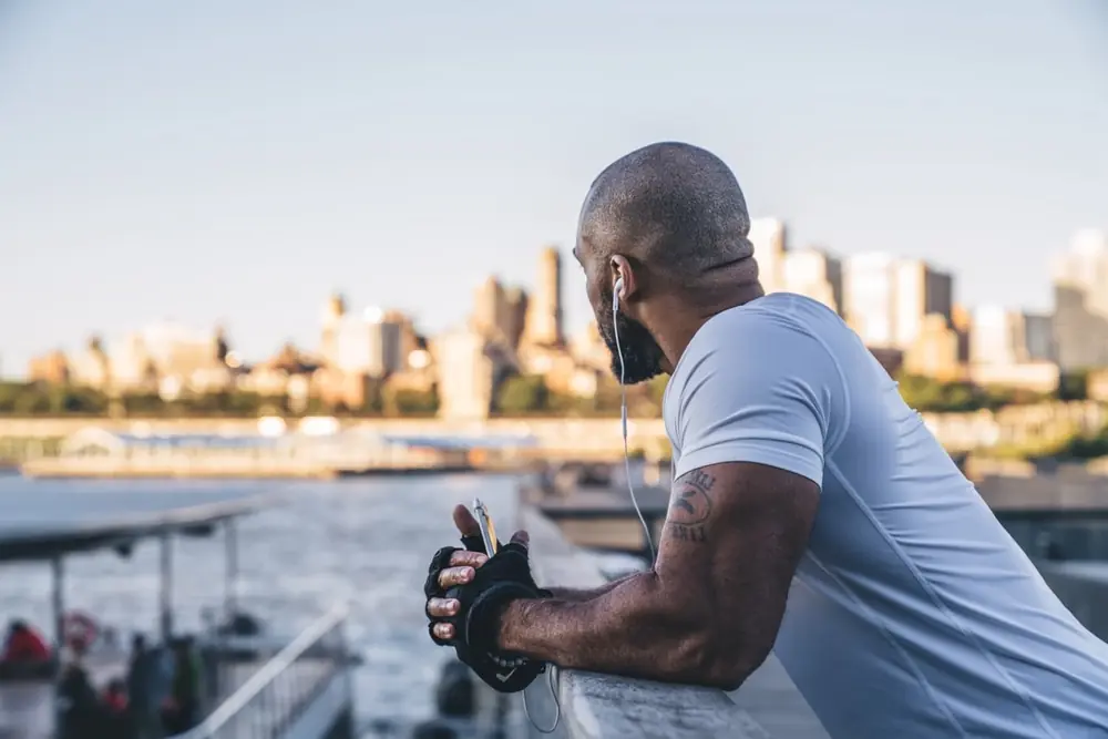 A man sits outdoors beside the water.