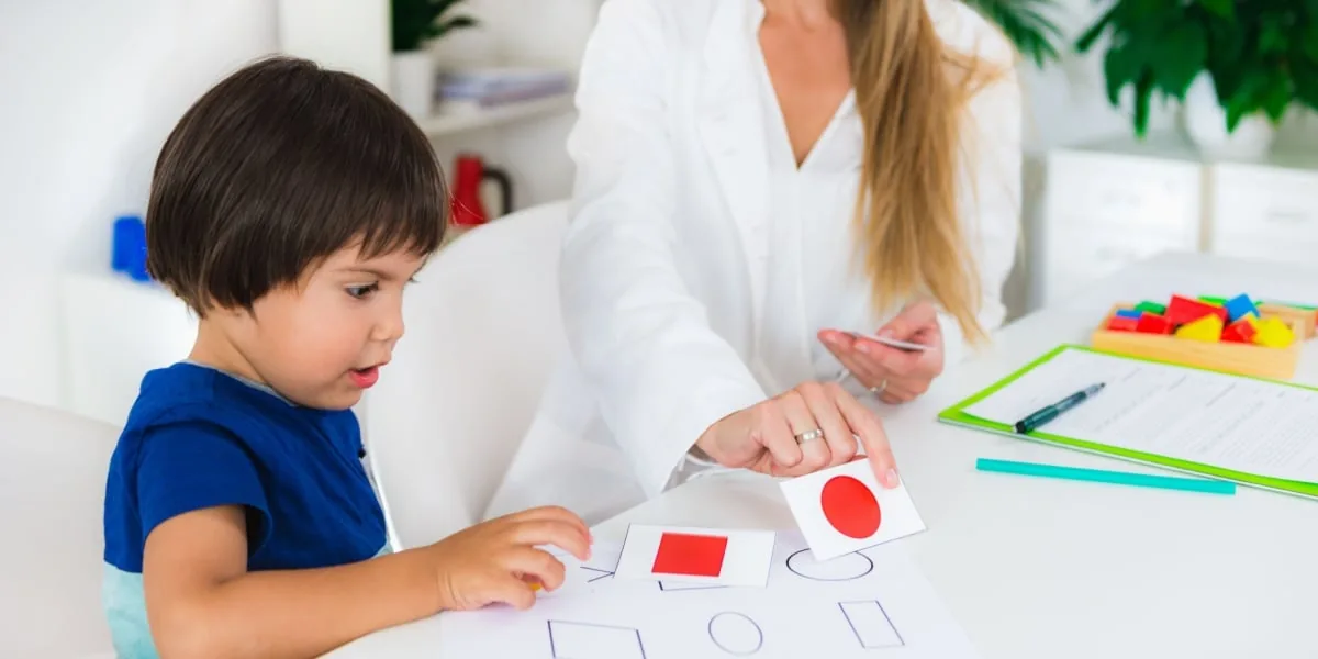 An adult helps a child complete an activity at a table.