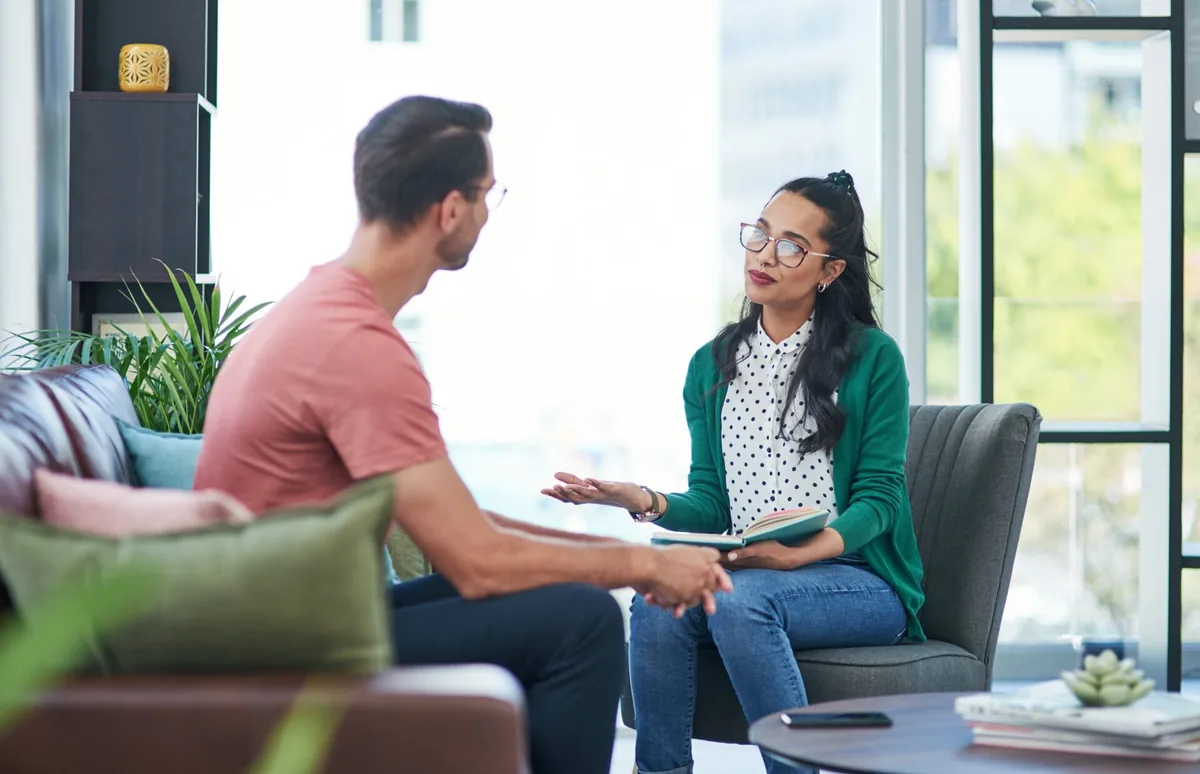 A woman speaks with a counselor in a bright room.