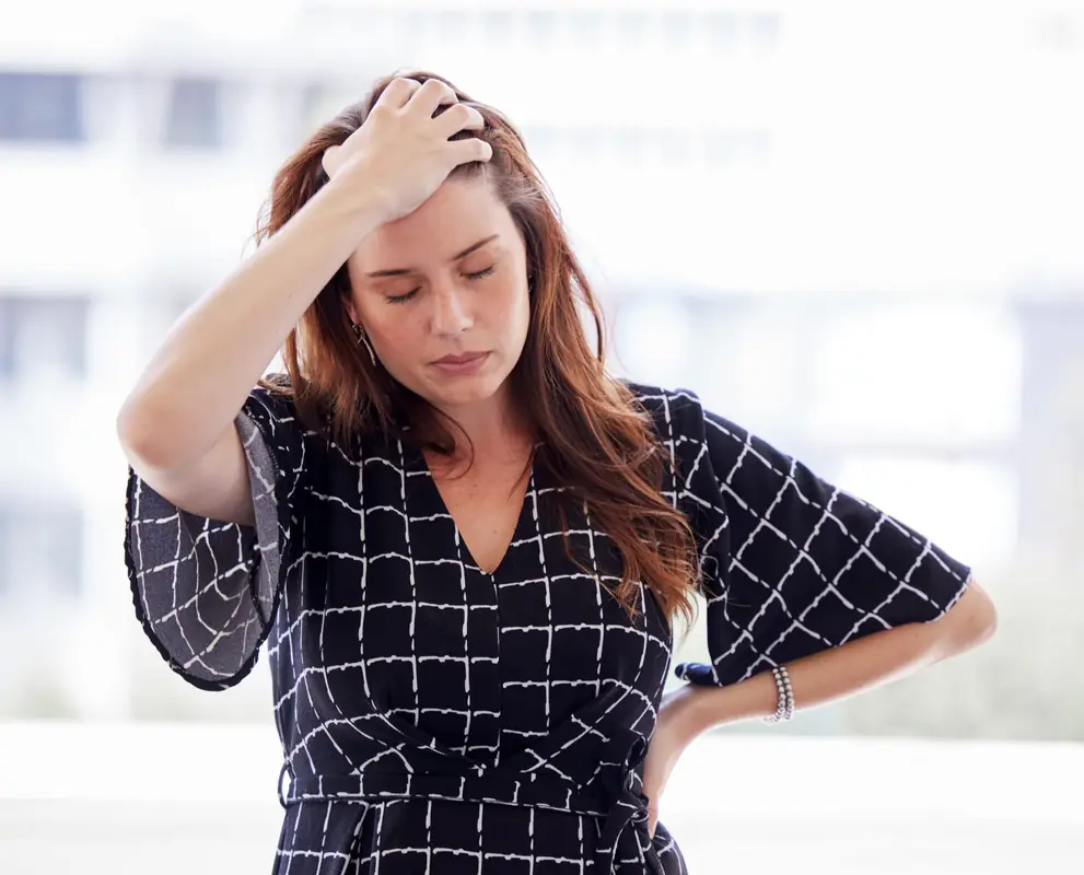 A woman rests her hands on her head.
