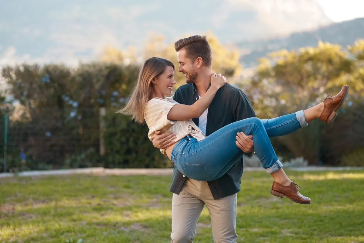 A couple embraces while standing outdoors beneath a wide sky.