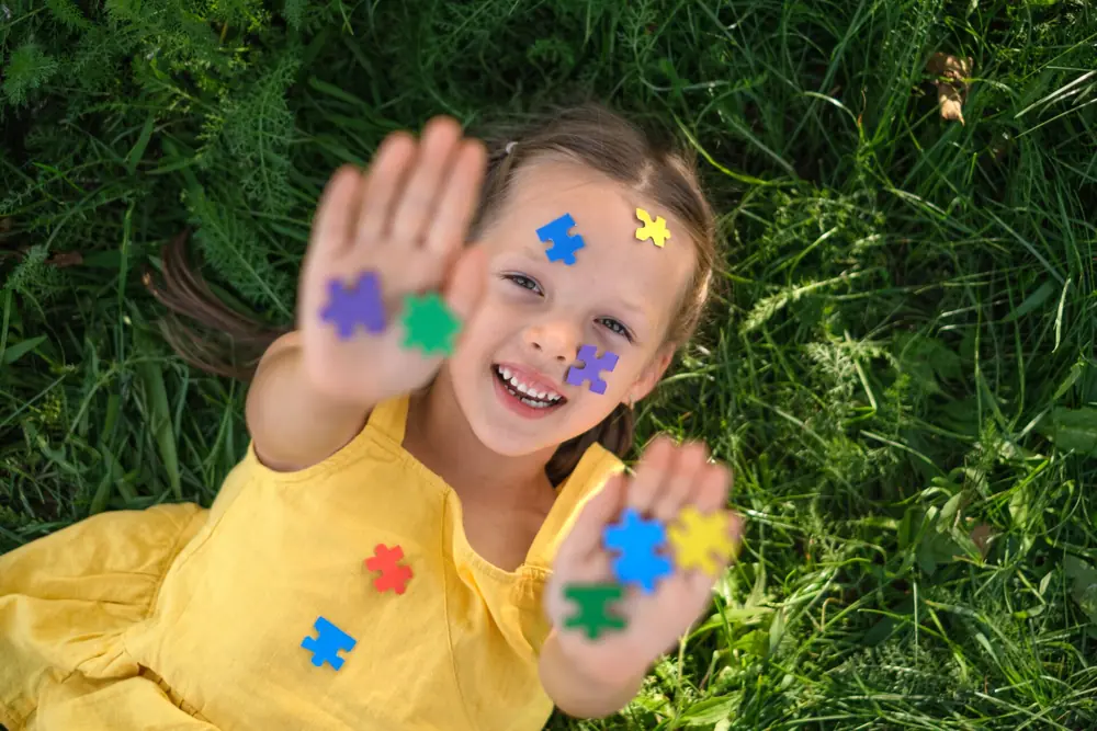 A child smiles while showing hands covered in colorful paint.
