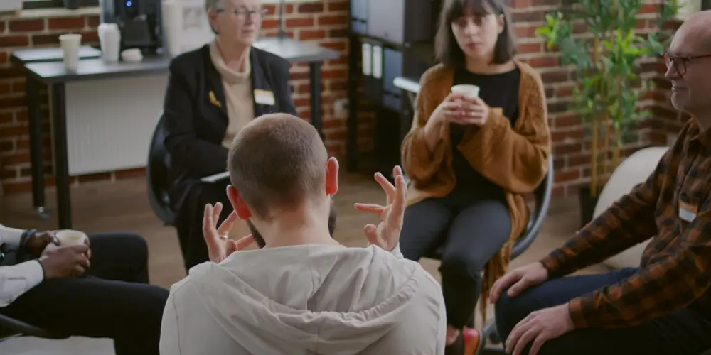 Adults sit in a circle during a group discussion.