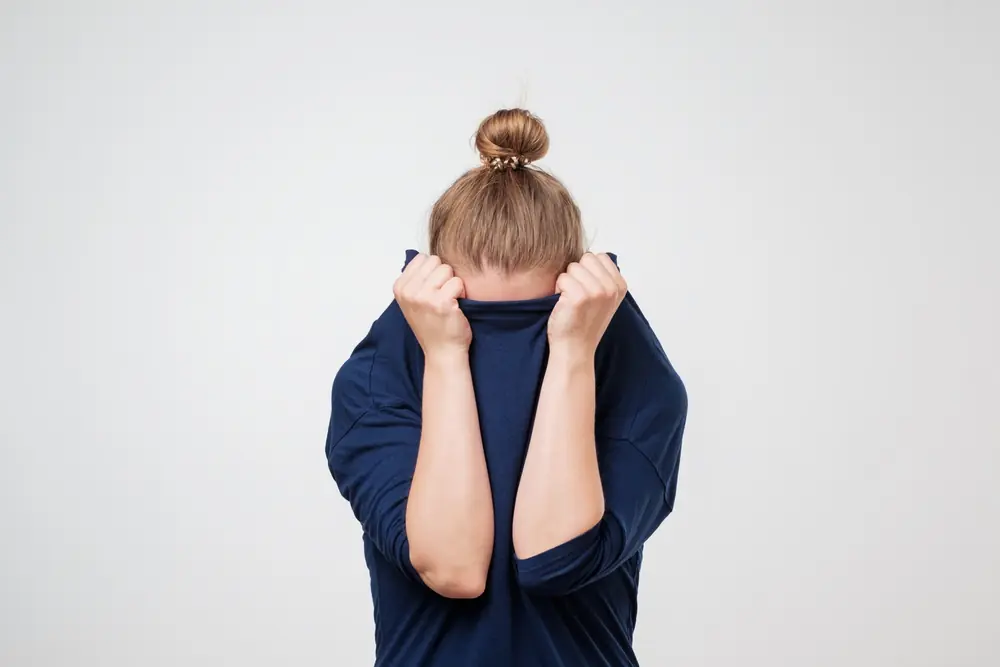 A woman sits with her knees drawn up.