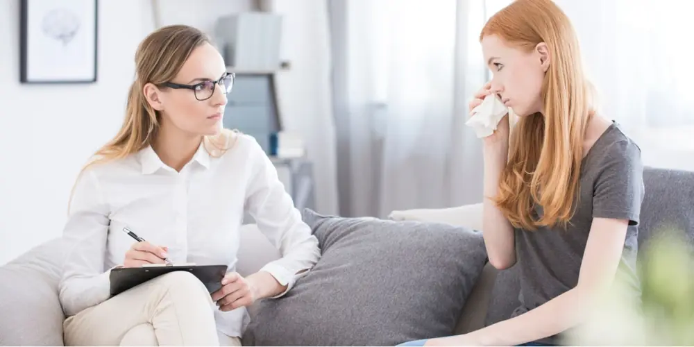 Two adults talk in a bright counseling room.
