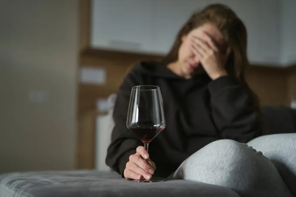 A woman sits thoughtfully on a sofa.
